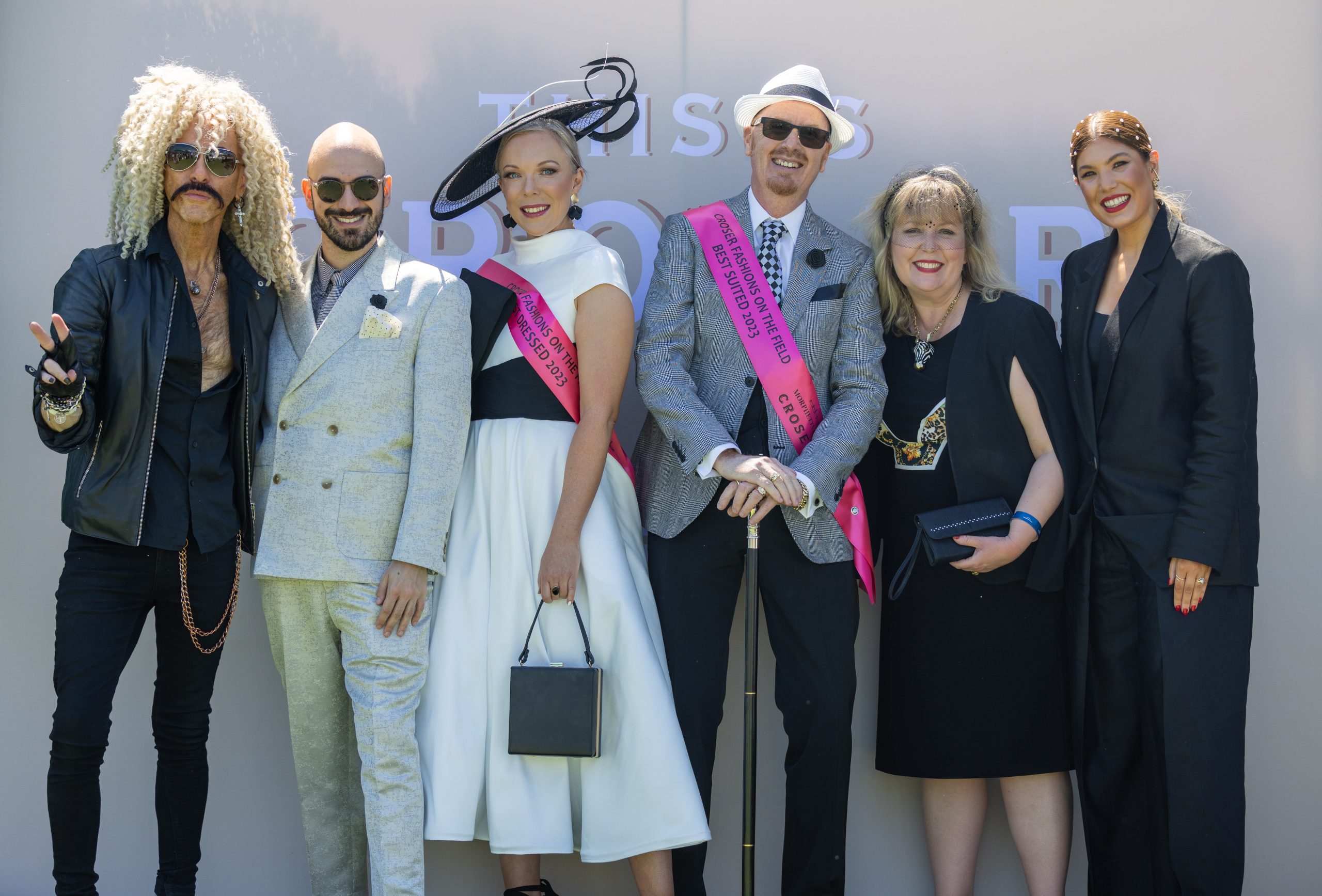 Fashions on the Field winners and judges pose for photo in front of Croser media wall